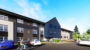 Waterloo apartment for rent - A person rides a bicycle in front of a parking lot with cars and a building.