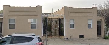 Long Beach apartment for rent - A tan building with a black gate in front.