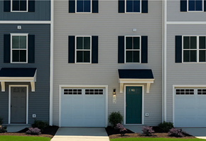 Charlotte house for rent - A grey building with a green door and white garage doors.