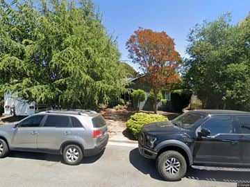 Soquel house for rent - Two cars are parked on a street with trees and a house in the background.