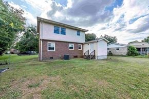 Jacksonville house for rent - A house with a white and brick exterior is surrounded by a grassy area.