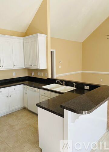 Winterville house for rent - A kitchen with white cabinets and a black countertop.