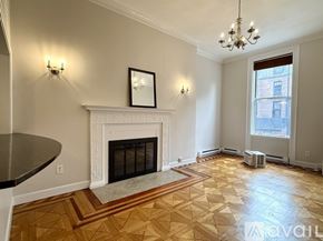 Boston apartment for rent - A living room with a fireplace, a sofa, a coffee table, and a chandelier.