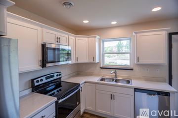 Marshfield house for rent - A kitchen with white cabinets and a black stove top oven.