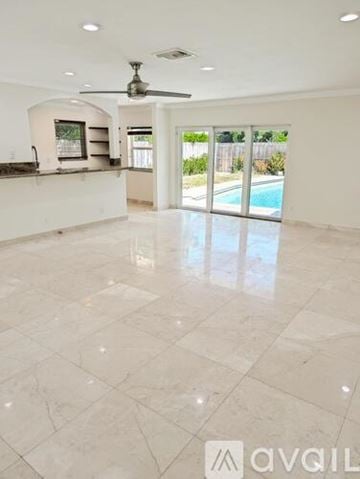 Boca Raton house for rent - A living room with a beige couch and a television on the wall.