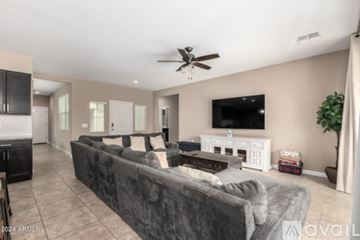 Buckeye house for rent - A living room with a grey couch and a television on the wall.