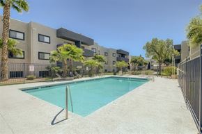 Mesa apartment for rent - A swimming pool in front of a building surrounded by palm trees.