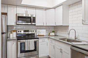 Phoenix apartment for rent - A modern kitchen with white cabinets and stainless steel appliances.