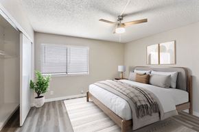 Phoenix apartment for rent - A bedroom with a bed, a plant, and a ceiling fan.