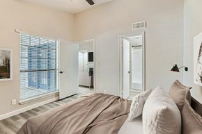 Dallas apartment for rent - A bedroom with a large bed and a window with blinds.