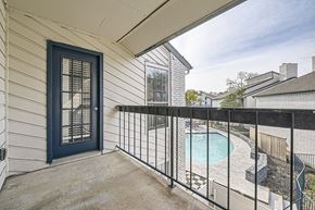 Dallas apartment for rent - A balcony with a black railing and a blue door overlooks a pool.
