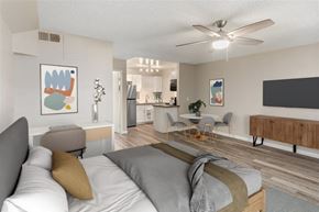Phoenix apartment for rent - A modern bedroom with a large bed and a kitchen area in the background.
