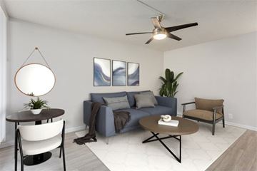Tempe apartment for rent - A living room with a grey couch, a brown armchair, a round table with a plant on it, and a painting on the wall.