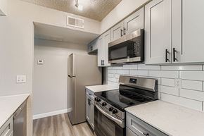 Bedford apartment for rent - A kitchen with white cabinets and black appliances.