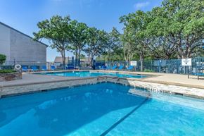 Bedford apartment for rent - A large outdoor swimming pool surrounded by trees.