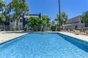 Glendale apartment for rent - A swimming pool in front of a building with a fence and trees.