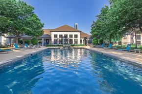 Northlake apartment for rent - A swimming pool in front of a building with trees on the sides.
