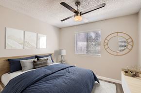 Phoenix apartment for rent - A bedroom with a bed, a ceiling fan, and a round mirror on the wall.