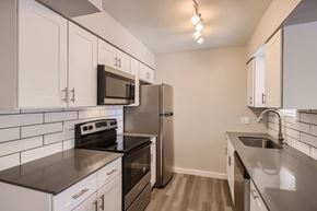 Phoenix apartment for rent - A kitchen with white cabinets and black countertops.