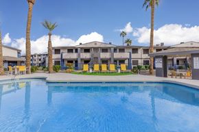 Phoenix apartment for rent - A swimming pool in front of a building with palm trees.