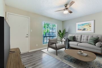 Phoenix apartment for rent - A living room with a grey couch, a wooden coffee table, a ceiling fan, and a painting on the wall.