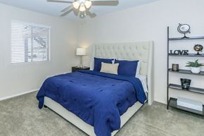 Phoenix apartment for rent - A bedroom with a bed covered in a blue comforter and a white headboard.