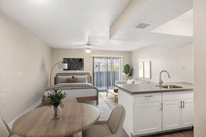 Phoenix apartment for rent - A modern kitchen with a dining table and chairs in the foreground and a bedroom in the background.