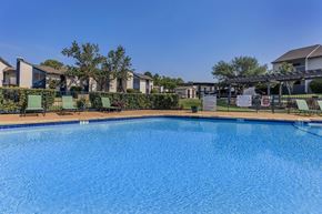Bedford apartment for rent - A large swimming pool in front of a building with a clear blue sky.