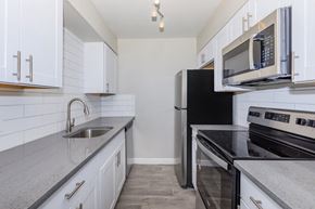 Phoenix apartment for rent - A kitchen with white cabinets and black appliances.