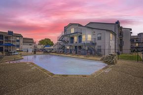 Mesquite apartment for rent - A swimming pool surrounded by apartment buildings at dusk.