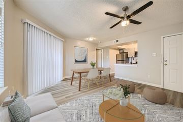Haltom City apartment for rent - A living room with a ceiling fan and a dining table with chairs.