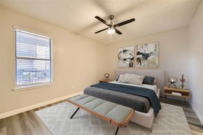Haltom City apartment for rent - A bedroom with a bed, a ceiling fan, and a window with blinds.