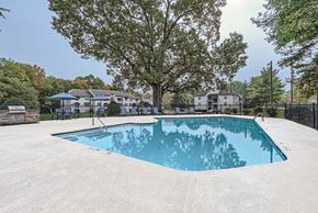 Matthews apartment for rent - A large swimming pool surrounded by a fence and trees.