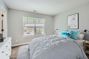 Matthews apartment for rent - A bedroom with a large bed and a window overlooking a street.