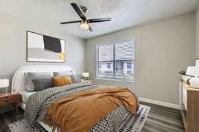 Garland apartment for rent - A bedroom with a bed covered in a brown blanket and a ceiling fan above it.