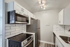 Garland apartment for rent - A kitchen with a black stove top oven and a black microwave above it.