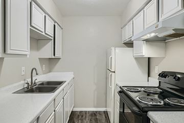 Dallas apartment for rent - A kitchen with white cabinets and a black stove top oven.