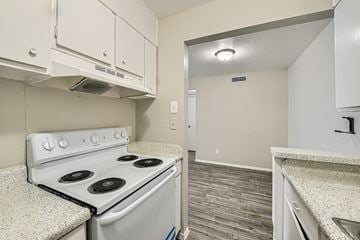 Dallas apartment for rent - A kitchen with a white stove top oven and white cabinets.