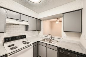 Fort Worth apartment for rent - A kitchen with a white stove top oven and a black dishwasher.