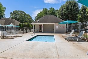 Greensboro apartment for rent - A pool area with a small building and lounge chairs.