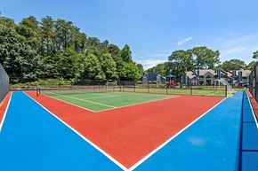 Greensboro apartment for rent - A tennis court with a red and blue surface surrounded by a fence.