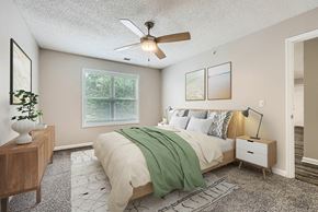 Charlotte apartment for rent - A bedroom with a bed, nightstand, and a ceiling fan.