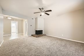 Fort Worth apartment for rent - A living room with a fireplace and a ceiling fan.