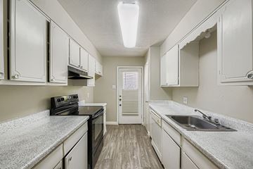 Fort Worth apartment for rent - A kitchen with white cabinets and a black stove top oven.