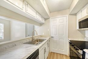 Garland apartment for rent - A kitchen with a white counter top and black appliances.
