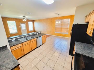 Killeen house for rent - A kitchen with wooden cabinets and a black refrigerator.