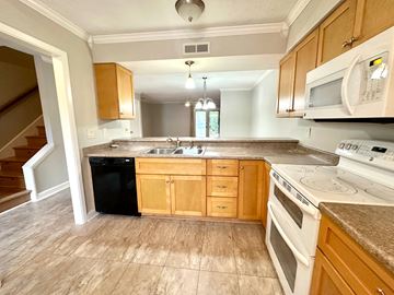 Simpsonville house for rent - A kitchen with wooden cabinets and white appliances.