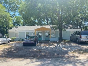 North Charleston apartment for rent - A white house with a yellow door is surrounded by trees and has two cars parked in front.