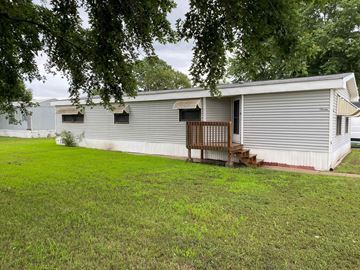 Kearney apartment for rent - A mobile home with a porch and a tree in the foreground.