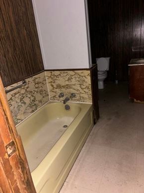 Prentiss apartment for rent - A dirty bathroom with a claw foot tub and a toilet in the background.